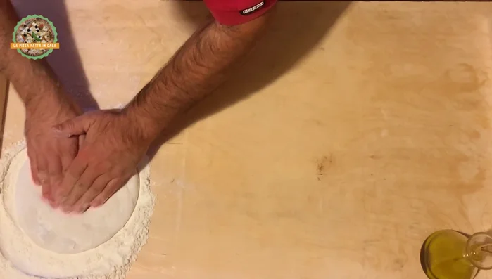 Preparare la pasta per pizza. Stendere la pasta sulla superficie infarinata, dandole una forma circolare.
