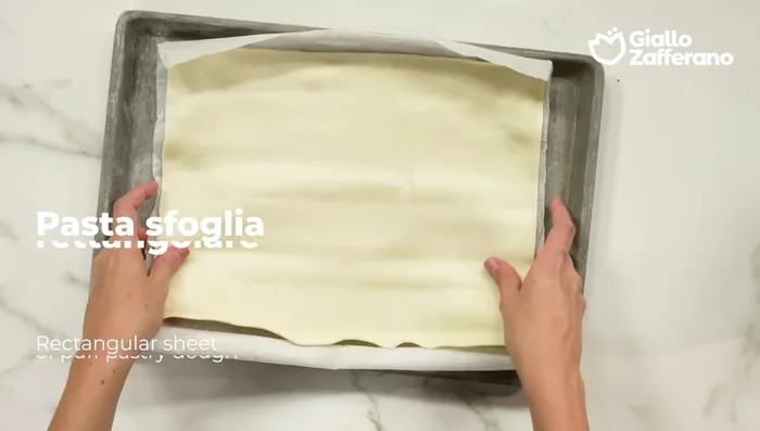Srotolare la pasta sfoglia e spalmare il ripieno su metà della superficie, lasciando circa 3 cm di bordo libero.