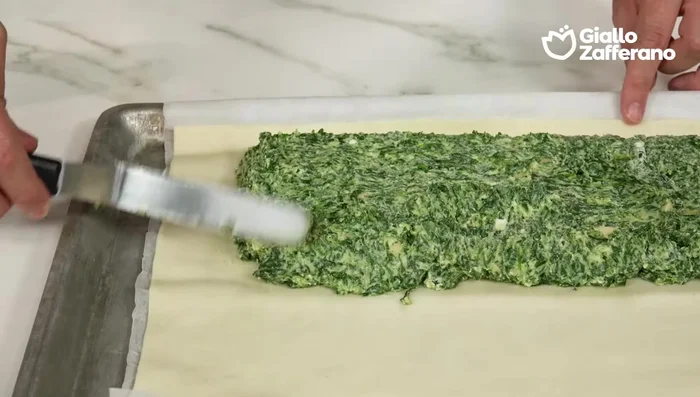 Ripiegare i due lati corti della pasta sfoglia sopra il ripieno e poi ripiegare la parte inferiore sopra il ripieno.
