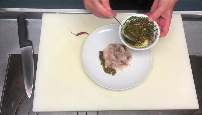 Una volta cotto, adagiare il pesce nel piatto e condire con la salsa alle erbe aromatiche preparata in precedenza.