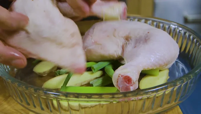 Appoggiare le cosce di pollo sopra lo zenzero e il cipollotto nel cestello. Aggiungere altre fette di zenzero e cipollotto sopra e coprire.