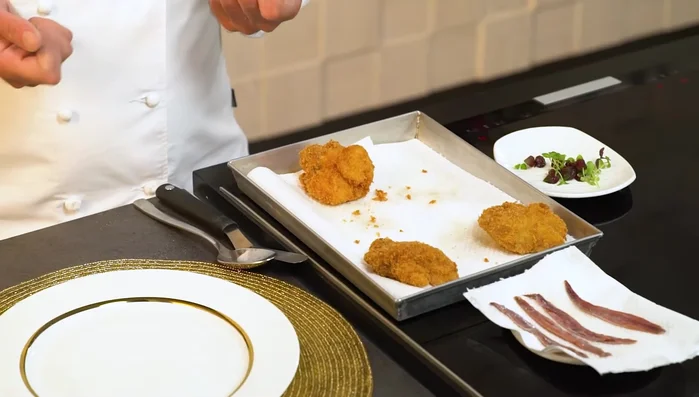 Impiattare: condire le animelle fritte con polvere di origano e polvere di pomodoro, aggiungere la salsa di pomodoro ridotta e le alici. Decorare con un elemento vegetale a piacere. (151.319)