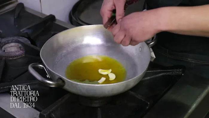In una padella, metti olio, aglio e peperone crusco tagliato a pezzi. Aggiungi anche la fogliolina di alloro.