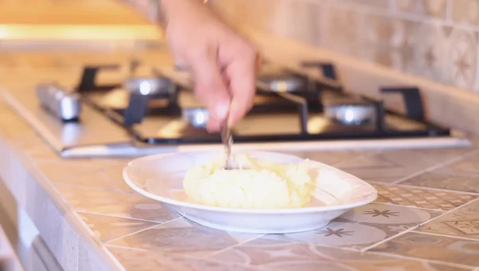 Mescolare il purè di patate con 2 tuorli d'uovo e 100 grammi di farina fino ad ottenere un impasto omogeneo.