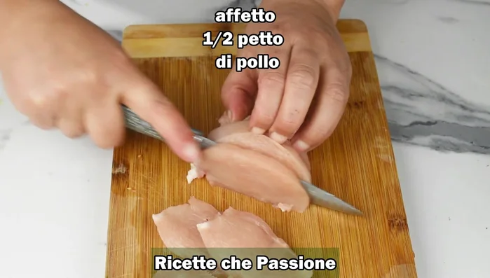Affettare il petto di pollo e infarinare.