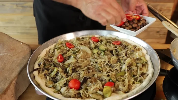 Aggiungere la mozzarella, le olive, i pomodorini, il basilico, l'origano e altri condimenti a piacere.