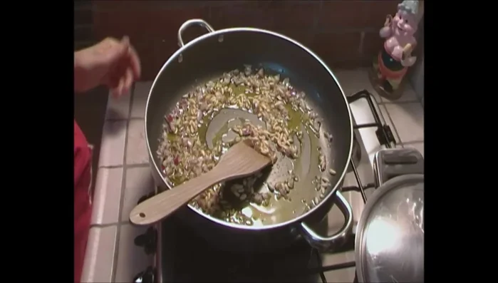 Aggiungere i pinoli e l'uvetta nella padella e farli tostare leggermente.