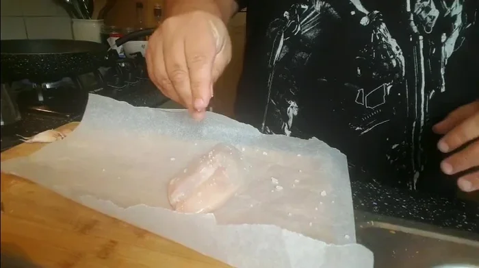 Su un foglio di carta da forno, posizionare il petto di pollo, salarlo, peparlo e aggiungere il rosmarino.