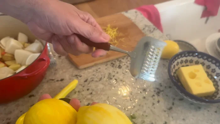 Grattugiare la scorza di due limoni.