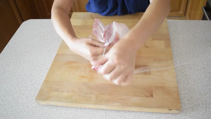 Legare il carrè di maiale con lo spago da cucina, facendolo passare sotto la carne e annodandolo lungo le costole.