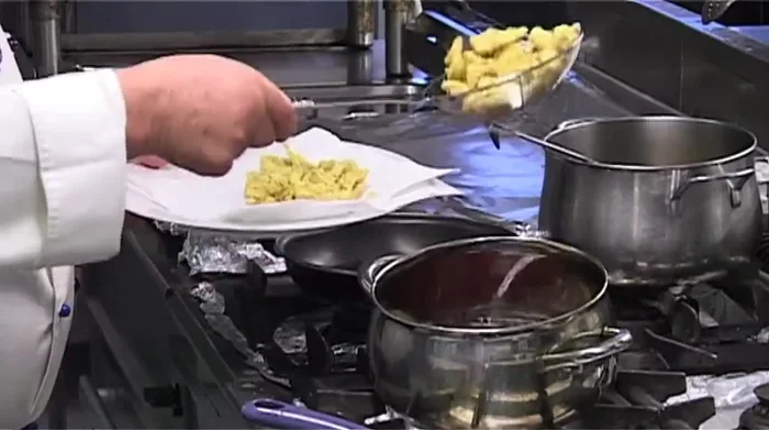 Scolare i carciofi fritti e metterli su carta da cucina per eliminare l'olio in eccesso (241.12)