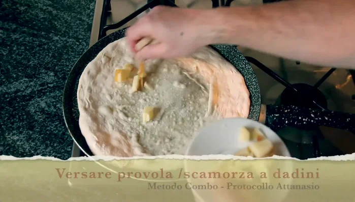 Versare la provola e la scamorza a dadini, coprendo bene il disco di pasta.