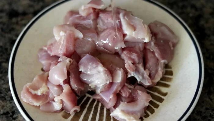 Tagliare le cosce di pollo a pezzetti (60.78). Condire con olio, sale e pepe. Mescolare con le mani (79.159).