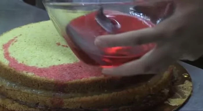 Coprire la torta con glassa reale (o crema al burro) e decorare con confettini, codette e mandorle tostate tritate.