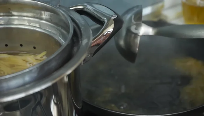Scolare la pasta nella padella con i gamberi, aggiungendo le scorze di limone (222.5).