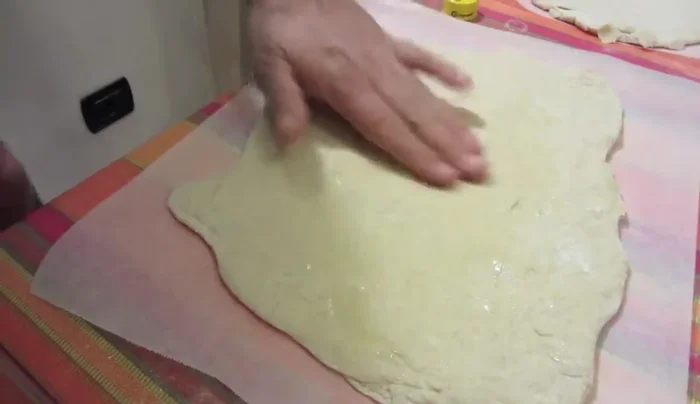 Oliate la base della pizza con olio d'oliva extravergine, distribuendolo uniformemente su tutta la superficie.