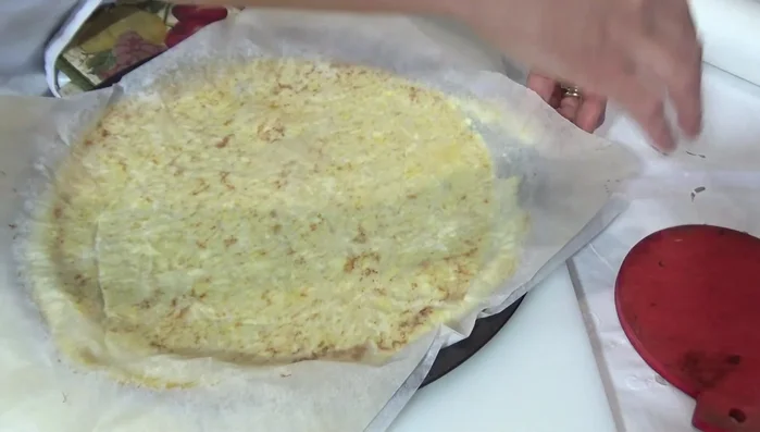 Capovolgere delicatamente la base cotta su un altro foglio di carta forno.