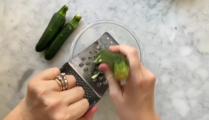 Preparare le zucchine e lo speck: Lavare e grattugiare le zucchine (123). Aggiungere sale e farle riposare (130.38). Tagliare lo speck a listarelle (137.89).