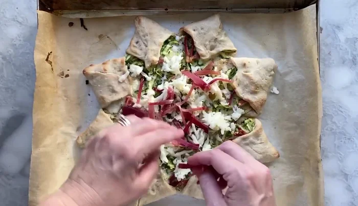 Aggiungere formaggio e speck: Togliere la pizza dal forno, aggiungere il formaggio e lo speck rimanenti e cuocere per altri 10 minuti (257.06).