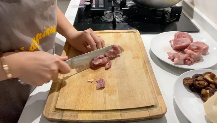 Tagliare la carne di maiale a pezzi di dimensioni uniformi. Tagliare anche il bambù, i funghi, lo zenzero e l'aglio in modo simile alla carne per un risultato più omogeneo.