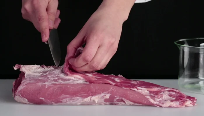 Puliamo e sgrasiamo il filetto di maiale, separando gli scarti più magri per la salsa.