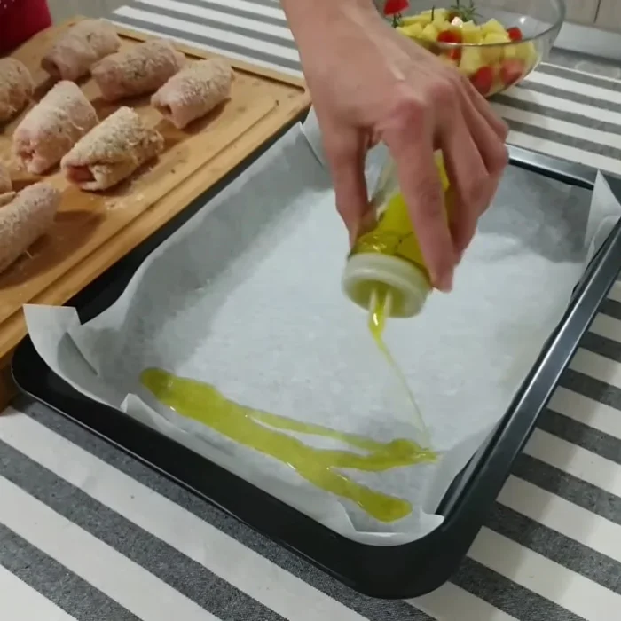 In una teglia, versiamo un filo d'olio extravergine di oliva, posizioniamo gli involtini e le patate con i pomodorini.