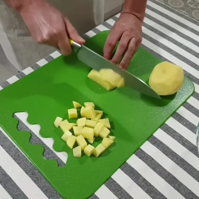 Prepariamo le patate: tagliamo le patate a dadini, aggiungiamo pomodorini a spicchi, sale, rosmarino e olio extravergine di oliva.