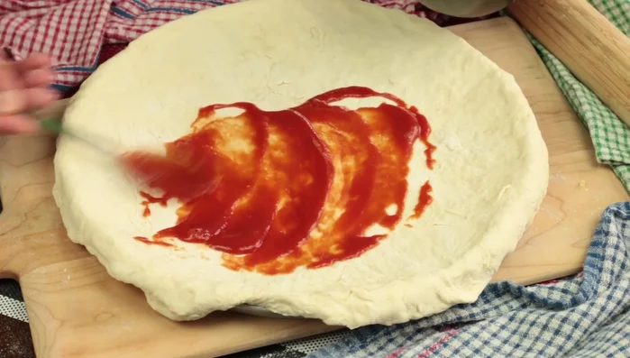 Distribuire la salsa di pomodoro su tutta la superficie della pizza. [73.32]