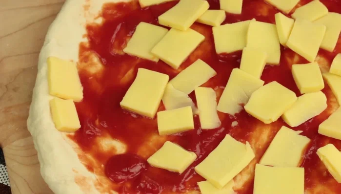 Aggiungere cubetti di mozzarella sul bordo della pizza. [81.119]