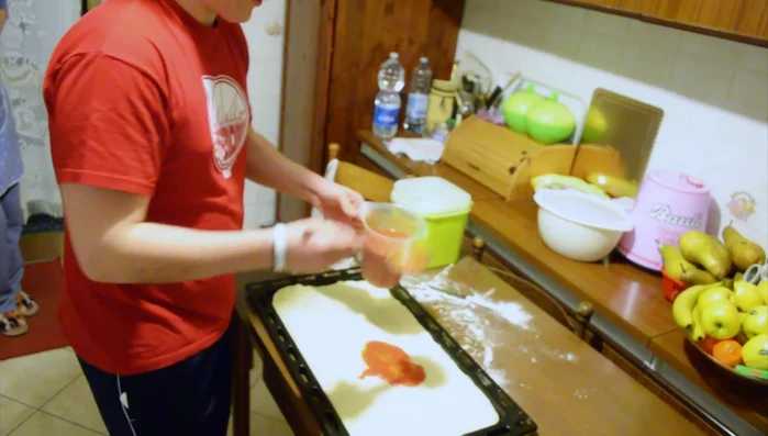 Spalmare i pelati sulla base di pizza, creando uno strato sottile.