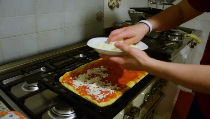 Aggiungere la mozzarella grattugiata sulla pizza cotta.