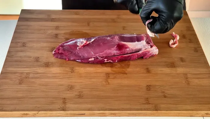 Eliminare le guaine di grasso e la pellicola argentata dal filetto di maiale con un coltello affilato. Rifilare le parti più sottili.