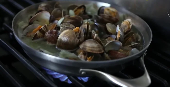 Se necessario, ridurre il fondo di cottura facendolo bollire in un tegame con un filo d'olio, aglio, vino bianco (fatto evaporare) prima di unire le vongole.