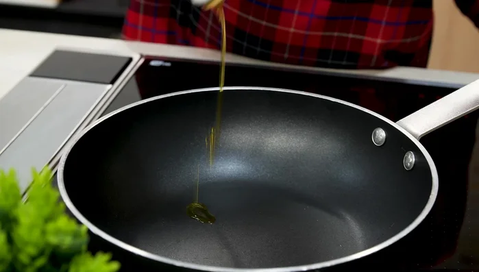 In una padella, soffriggere leggermente l'aglio a fette nell'olio. Togliere l'aglio e aggiungere le tagliatelle di calamari, saltandole per un paio di minuti.