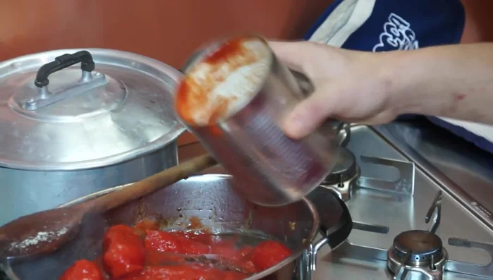 Aggiungere i pelati e il brodo: Aggiungere i pelati, un po' di brodo (utilizzando il barattolo dei pelati per raccogliere il liquido), sale e pepe. Mescolare e far cuocere a fuoco lento per circa 3 ore, rigirando di tanto in tanto, fino a che il sughetto non si sarà addensato e la carne sarà tenera.