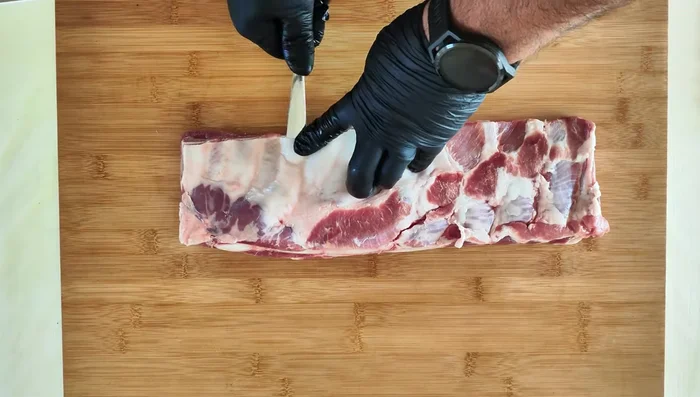 Rimuovi la membrana sul lato delle ossa del costato di maiale usando il retro di un cucchiaio e tirando con decisione. (21.72)