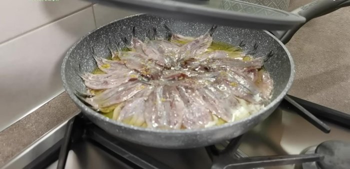 Coprite la padella e lasciate sobbollire per circa un minuto, finché le alici non cambiano colore, diventando chiare.