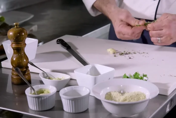 Preparare la crosta di erbe: tritare finemente aglio, timo, rosmarino e prezzemolo. Aggiungere il parmigiano e il pangrattato, mescolando fino ad ottenere un composto omogeneo di colore verde.