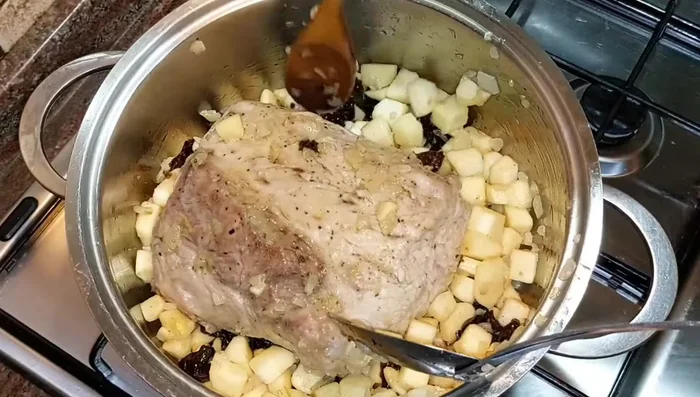 Aggiungete le mele e le prugne intorno all'arista. Unite un mix di acqua e vino, due pizzichi di sale grosso. Coprite e lasciate cuocere per almeno un'ora, mescolando di tanto in tanto.