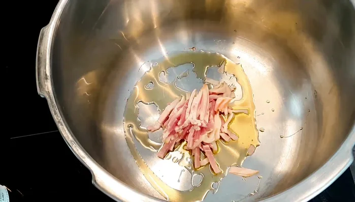 In una pentola, mettere un po' d'olio extravergine di oliva e soffriggere la pancetta a fuoco medio fino a renderla croccante.