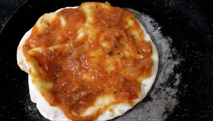 Aggiungere la salsa di pomodoro sulla base della pizza.