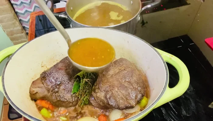 Aggiungere il brodo caldo (preparato con acqua, dado vegetale/carne) fino a quasi coprire la carne.