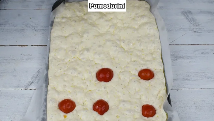 Farcire la pizza lievitata con pomodorini, provola affumicata, salsiccia e fiori di zucca (facoltativi).