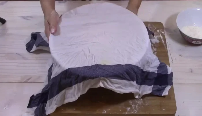 Far riposare l'impasto: Formare una palla, spolverare di farina, coprire con un canovaccio umido e lasciare riposare per 2 ore a temperatura ambiente.