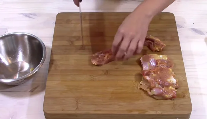 Preparare il pollo al curry: Tagliare il pollo a pezzi e cuocerlo a fuoco medio con latte di cocco, pasta di curry rosso, salsa di soia, zucchero, sale e metà del basilico per circa 5 minuti.