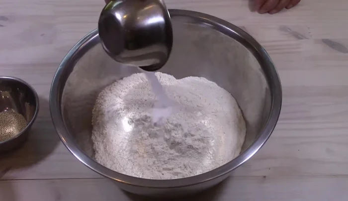 Preparare l'impasto: In una grande ciotola, mescolare farina e sale. Aggiungere gradualmente l'acqua tiepida (30°C) e l'olio d'oliva, impastando con una spatola. Trasferire l'impasto sulla spianatoia e impastare a mano per almeno 10 minuti, aggiungendo farina se necessario.