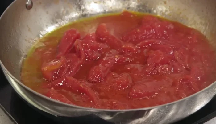 Aggiungere i pomodori pelati a filetti (San Marzano è preferibile) all'olio caldo. Mescolare e lasciare insaporire.