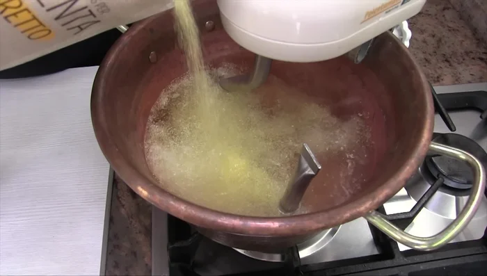 Aggiungere la polenta a pioggia, mescolando lentamente per evitare grumi. (97.6)