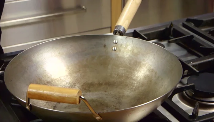 Scaldare 2 cucchiai di olio di sesamo nel wok. Aggiungere aglio e zenzero tritati e far soffriggere per circa 30 secondi.