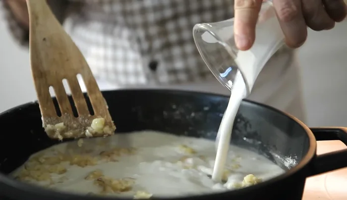 Aggiungere il latte di cocco e la parte di brodo messa da parte. Lasciar ridurre fino ad ottenere una consistenza cremosa. Condire con pepe di Cayenna.